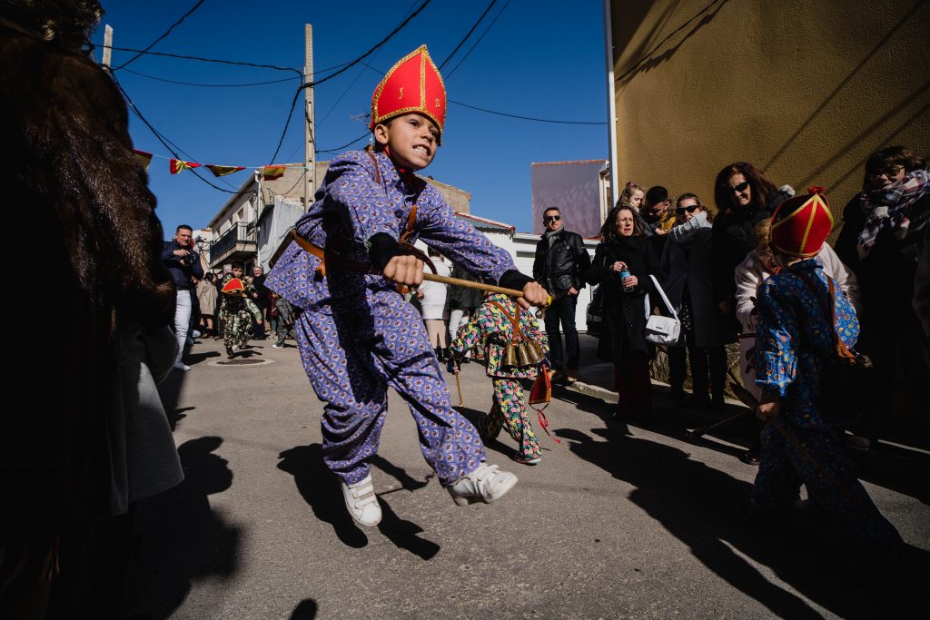 Un niño corriendo y saltando para hacer que resuenen los cencerros que tiene atados a la espalda durante la procesión en honor a san Blas | Foto: Pedro Pascual