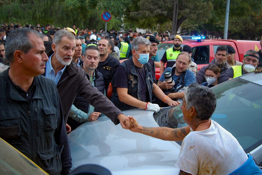 El Rey Felipe VI saluda a una vecina de Paiporta durante su visita a la DANA