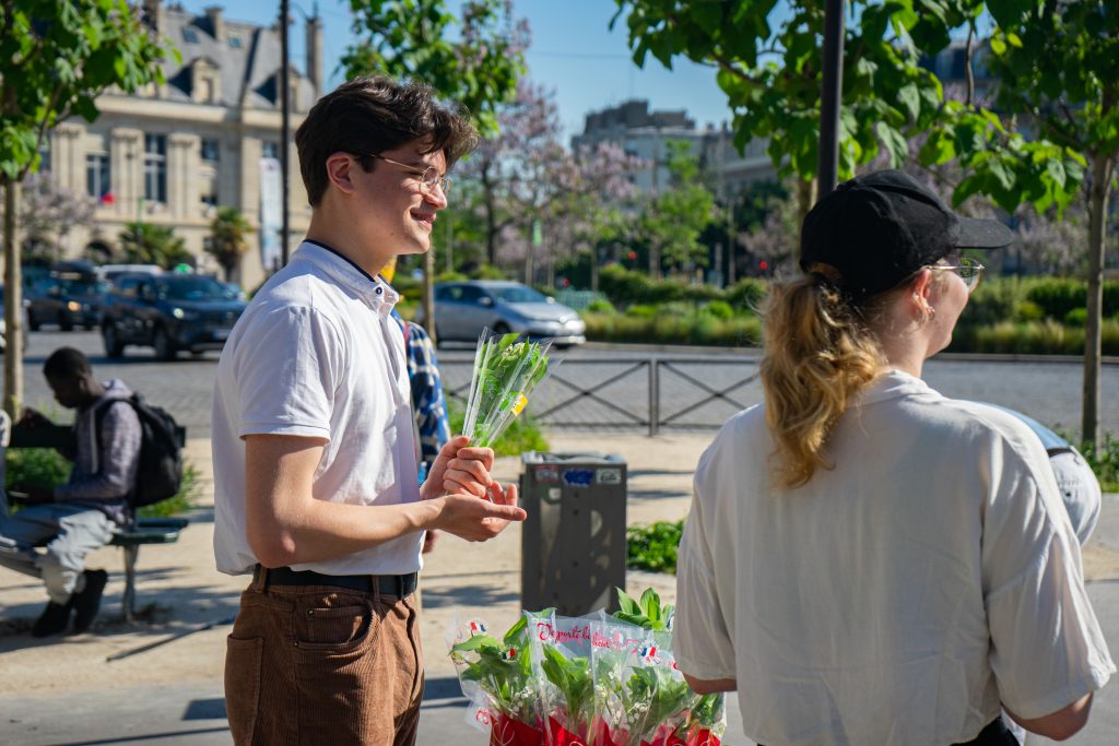 Unos jóvenes reparten los lirios del valle antes de la manifestación 