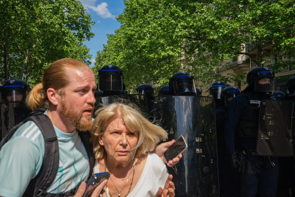 Una mujer se protege del enfrentamiento entre manifestantes y policías