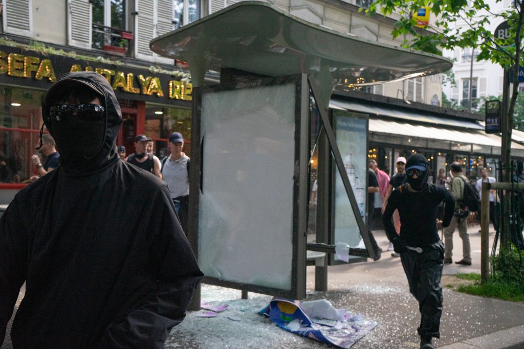 Los black blocs, encapuchados, corren tras romper una marquesina 